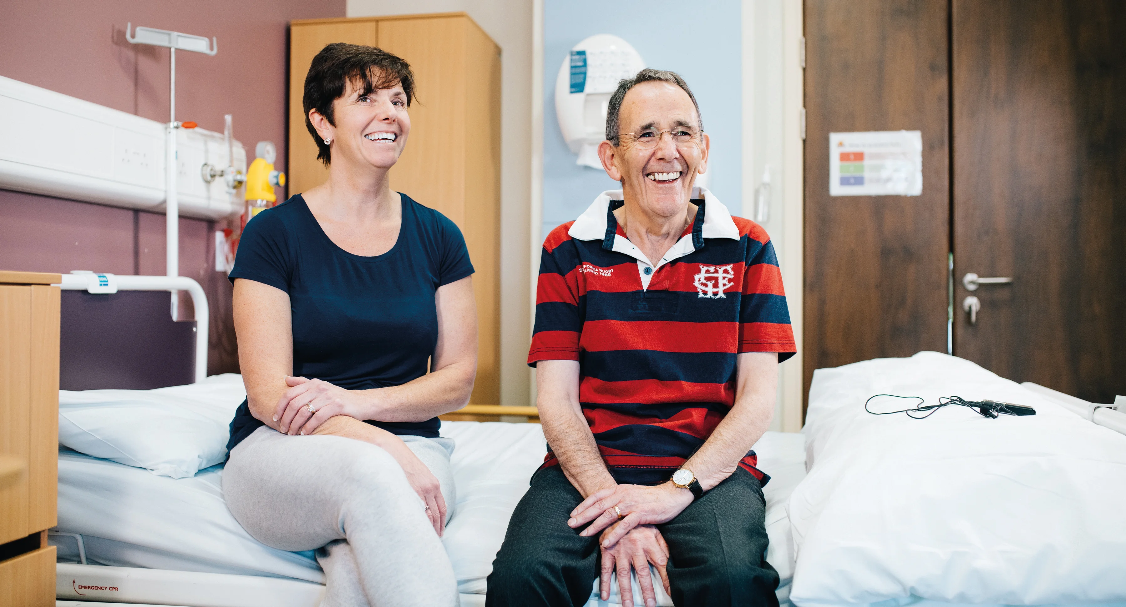 a man and a woman sitting on a hospital bed