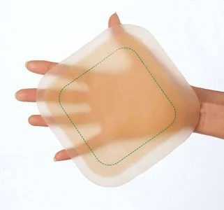 a hand holding a wound dressing