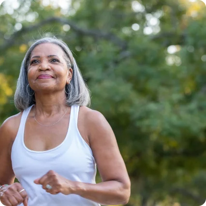 Una donna con un volto sorridente in mezzo al verde naturale.